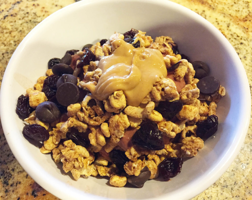 A frozen berry bowl with the works: cashew butter, Kashi cinnamon crisp cereal, dried cherries & dark chocolate chips